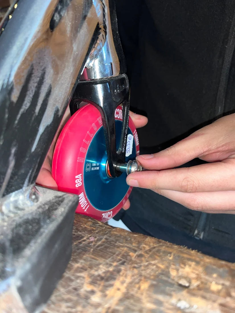 Gros plan sur le montage d’une roue rose dans une fourche chromée